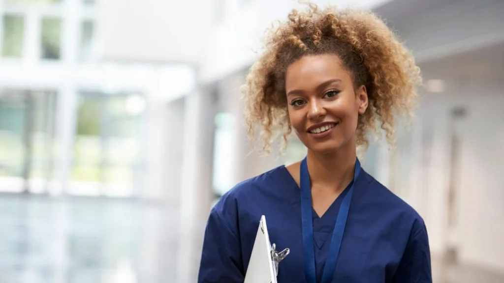 Enfermera sonriente con uniforme y carpeta en el pasillo de un hospital